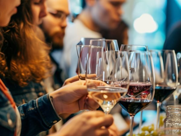 A diverse group of friends enjoying a sophisticated wine tasting event, savoring the flavors of various exquisite varieties. Laughter, conversation, and elegance fill the air as they raise t